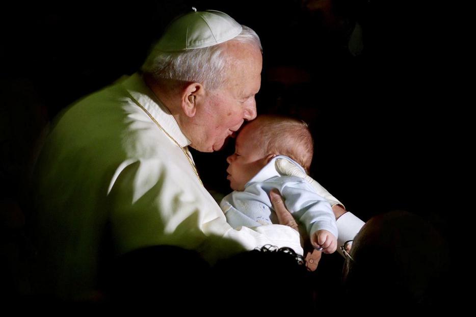 Pope John Paul II kisses a baby during a weekly general audience in November 2001.