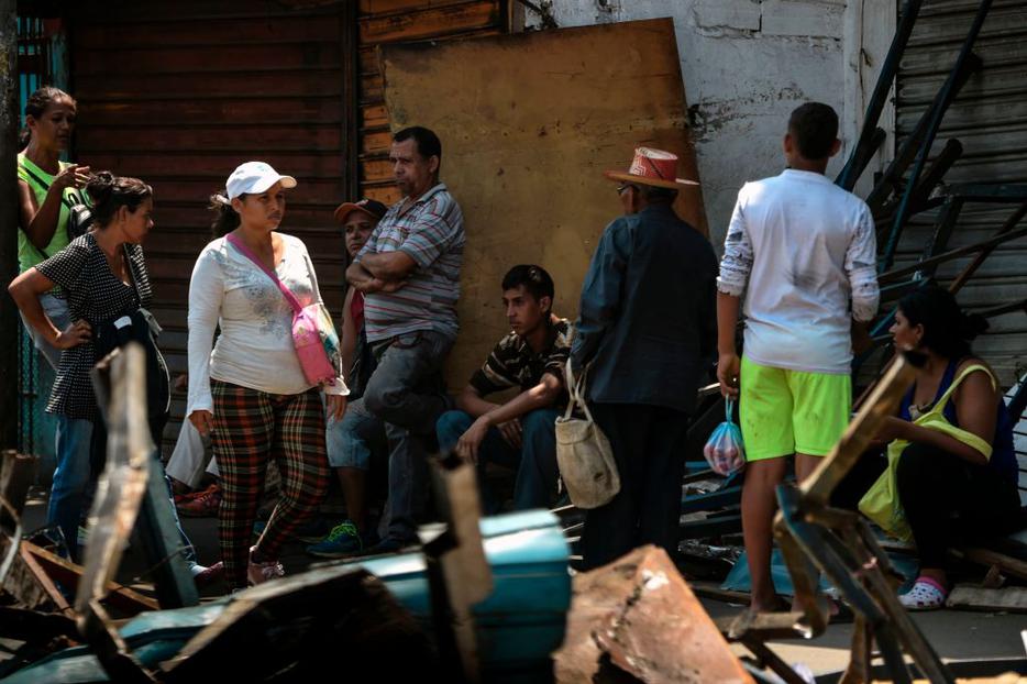 Locals sit and stand on the street March 13 in Maracaibo, in the border state of Zulia, during the massive blackout that has paralyzed Venezuela for days.
