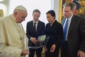 Zuckerberg and Chan presenting a gift to the Pope, accompanied by Vatican spokesman, Greg Burke. 
