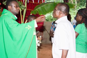 A priest offering communion inside a Catholic church within an African village. 