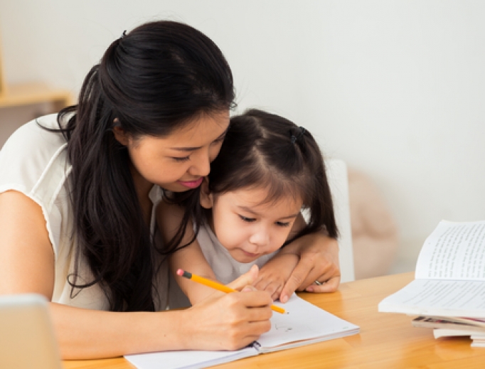 Mother teaching her young daughter how to write. 