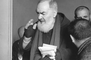 Padre Pio, bearing the stigmata, blesses the faithful.
