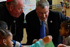 Cardinal Timothy Dolan and New York Mayor Bill de Blasio talk with students at St. Francis of Assisi School in the Bronx on March 6, 2014.