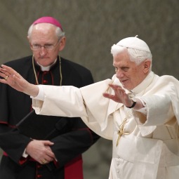 Pope Benedict XVI waves upon arriving to lead his general audience in Paul VI hall at the Vatican Nov. 24. In the background is U.S. Archbishop James Harvey, prefect of the papal household.