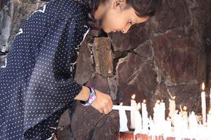 A young girl lights a candle at a Marian grotto in Pakistan.