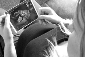 A mother holds a sonogram photo of her unborn child in her hands.
