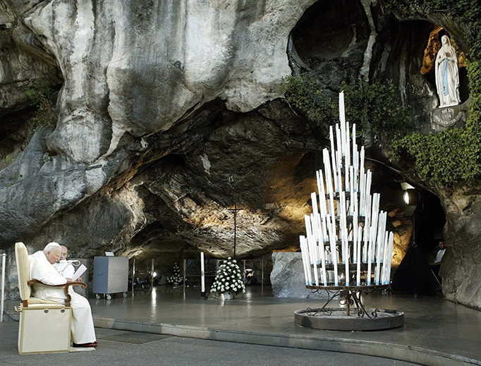 Racked by Parkinson’s disease and arthritis, Pope St. John Paul II prays in front of the Lourdes Grotto after a Rosary procession on Aug. 14, 2004.
