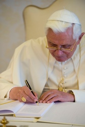 Pope Benedict XVI signs a copy of Caritas in Veritate July 6.