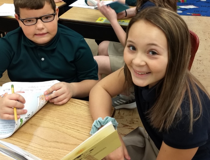 In Escanaba, Michigan, Holy Name Catholic School middle-school students often work with younger students on reading and comprehension. Above, 2020 eighth-grader Sophia Derkos and elementary student Nicholas Flath smile as they work together on a reading project. Below, Second photo: 2020 eighth-grader Natalie Williams reads with elementary students Kinley Hastings and Thomas Carlson. In the background, 2020 eighth-grader Annabelle Neumeier reads to elementary students.

