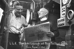 Msgr. Matthew Smith discusses a new issue of the National Catholic Register with Msgr. John Cavanaugh in the press room in Denver. 
