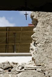 A crucifix hangs amid rubble of a destroyed house after the April 6 earthquake in Italy.