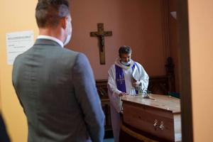A priest, wearing a protective mask, leads a religious ceremony on April 6, 2020 attended by a strictly limited number of relatives during the funerals of a 51-year-old woman. 