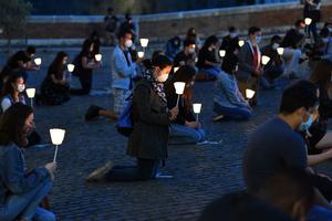Young Catholics kneel Tuesday at a prayer vigil for George Floyd outside the San Bartolomeo church on Isola Tiberina island in Rome.