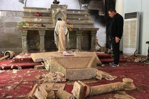 Priest examines ruins, including a decapitated statue of the Blessed Mother, in a Catholic church in Karamdes, Iraq, following the towns liberation from ISIS.