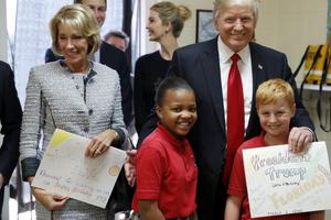 President Donald Trump and Education Secretary Betsy DeVos pose with fourth graders Janayah Chatelier, 10, left, Landon Fritz, 10, after they received cards from the children, during a tour of St. Andrew Catholic School March 3 in Orlando, Florida. 