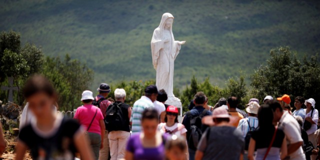 Pilgrims flock around a statue of Mary at Medjugorje.