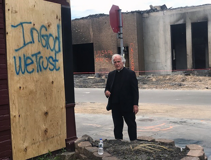 Above, Dominican Father Joseph Gillespie, the pastor of St. Albert the Great in south Minneapolis, stands by a hopeful message amid destruction in his parish neighborhood. The area was looted during violent protests following the death of George Floyd at the end of May.