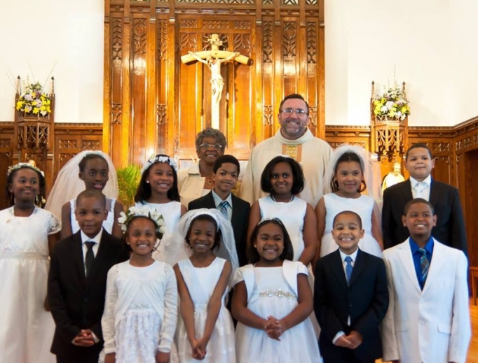 Father Christopher Walsh, shown with first communicants, says his close-knit Philadelphia parish of St. Raymond of Penafort is seeing collections up 2% from last year.

