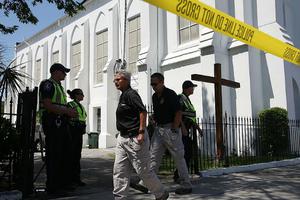 Police investigators walk in front of Emanuel AME Church  in Charleston, S.C., on June 18, 2015, one day after nine people were killed in a mass shooting during a prayer meeting at the church. 