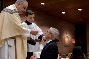 Above, Father John Mosimann, pastor of St. Mary of the Immaculate Conception parish in Fredericksburg, Virginia, gives David Bereit Communion during the Easter vigil Mass. Below, the Bereit family celebrates the new Catholic with Father Mosimann.
