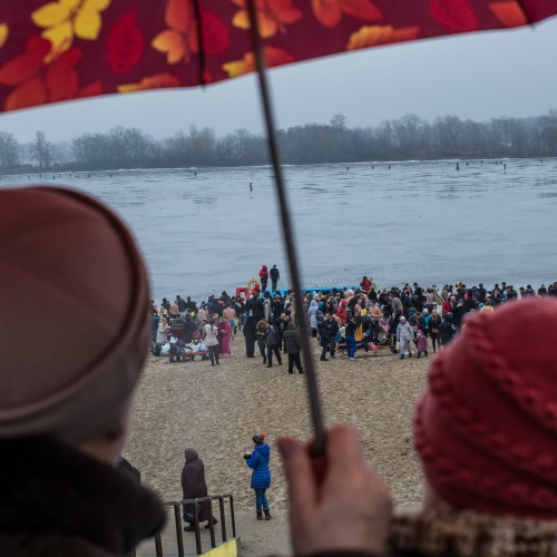 Women watch as Orthodox Christians stand on the beach after bathing, to symbolically wash away their sins, in the Dnieper River for Epiphany on Jan. 19 in Kiev, Ukraine. 