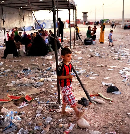 Iraqi families who fled recent fighting near the city of Mosul prepare to sleep on the ground as they try to enter a temporary displacement camp but are blocked by Kurdish soldiers July 3 in Khazair, Iraq.