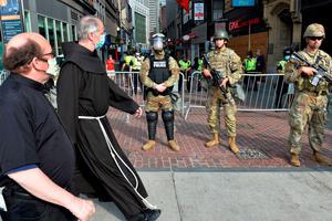 Two priests walk by National Guard Soldiers stationed in downtown Boston on Wednesday.