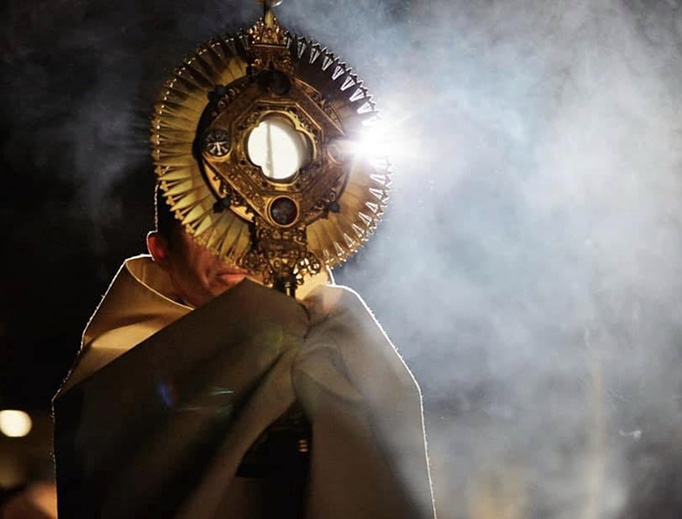 Father Michael Delcambre of Broussard, Louisiana, carries the Blessed Sacrament in procession.