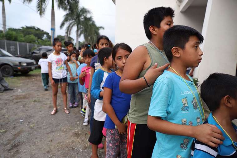 Children line up outside a shelter in Guatemala after a 2018 volcano eruption. 