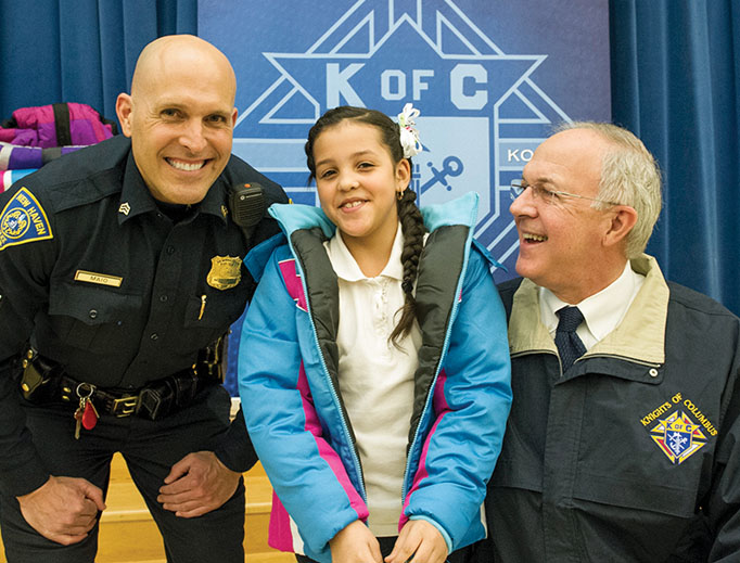 Supreme Knight Carl Anderson and New Haven police distribute coats during a 2016 ‘Coats for Kids’ event at a local school.
