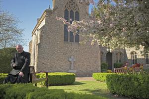 Msgr. John Armitage, shown enjoying the garden and praying at the Walsingham shrine, says, ‘Our Lady wanted us to make the dedication in the midst of this storm.’
