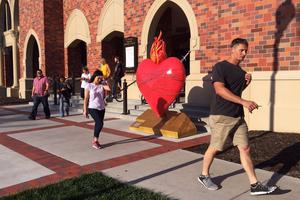 College students walk past a sculpture of the Sacred Heart at St. Thomas Aquinas Church on the University of Nebraska campus in Lincoln.