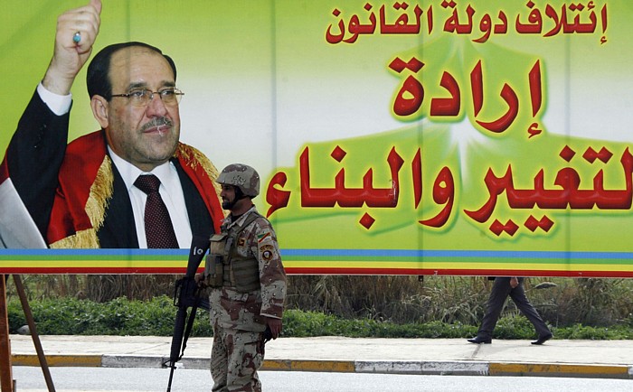 An Iraqi soldier stands guard near a campaign billboard of Iraq's Prime Minister Nuri al-Maliki in Mosul, Iraq, Feb. 24. The billboard reads "State of Law coalition, the willing of change and construction."
