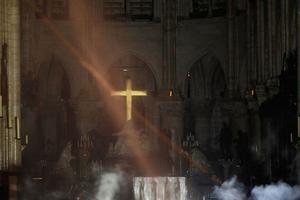 Smoke rises around the alter in front of the cross inside the Notre-Dame Cathedral as the fire continues to burn on April 16, 2019 in the French capital Paris.
