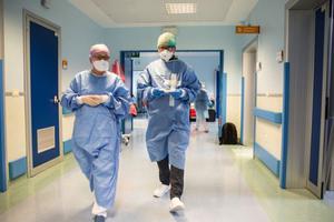 A priest (c) walks through the Intensive Care Unit and prepares to give a blessing and Holy Communion to patients for Easter on April 12 in Sant’Orsola Hospital in Bologna, Italy. Worldwide, including in the U.S., priests are suiting up in protective gear to anoint the sick amid the pandemic.