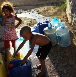 Syrian children fill cans with water June 28 at a Syrian refugee camp in Baalbek, Lebanon.