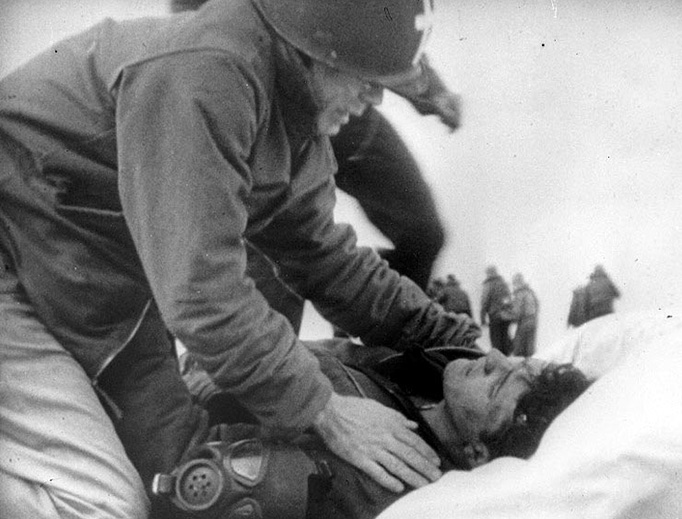 Father Joseph T. O'Callahan serves an injured crewman aboard the USS Franklin (CV-13), after the ship was set afire by a Japanese air attack on March 19, 1945 — the Feast of St. Joseph, the foster father of Jesus.