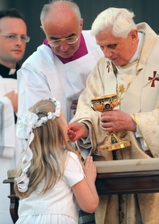 A girl kneels as she receives Communion from Pope Benedict XVI during Mass in May 2008.