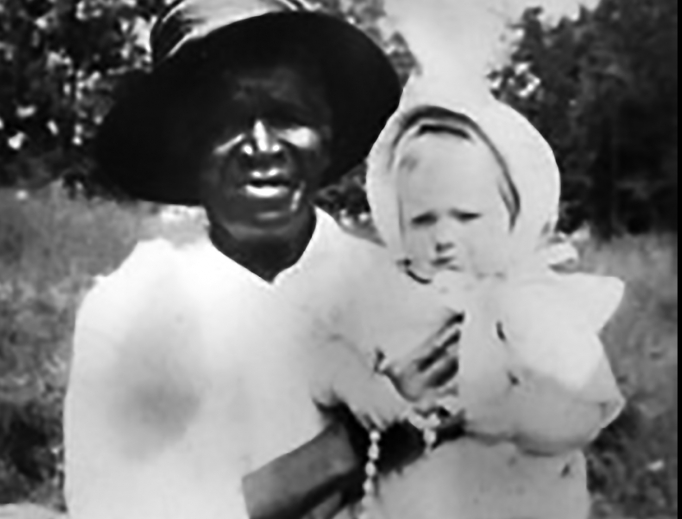 Above, the only photograph of Julia Greeley known to exist shows her holding 7-month-old Marjorie Ann Urquhart. Urquhart’s mother told Julia she had lost a child 13 years prior and was told she couldn’t have any more children. Greeley prayed for her, and, the next year, Marjorie was born. Below, Archbishop Samuel Aquila signs the oath pledging to fulfill faithfully the task of the cause and blesses the crowd at the Dec. 18 Mass.

