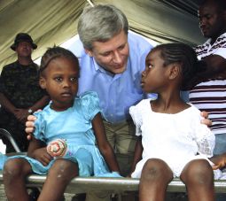 VISITOR. Canada's Prime Minister Stephen Harper talks with two Haitian girls as they wait for treatment at a Canadian medical clinic in Jacmel, Haiti, Feb. 16. At home, Harper is under fire for a proposal to lead G8 countries in a campaign to improve the health of mothers and children in the Third World — without provisions for abortion.