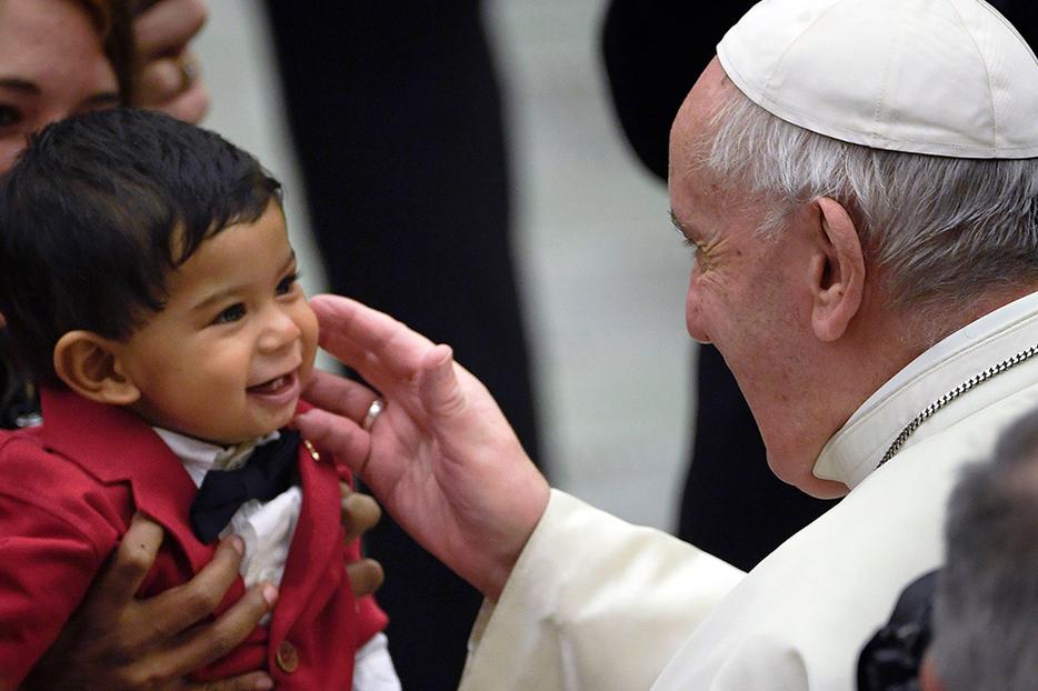 Pope Francis blesses a toddler at the weekly general audience Feb. 12 at the Paul VI Hall in the Vatican.