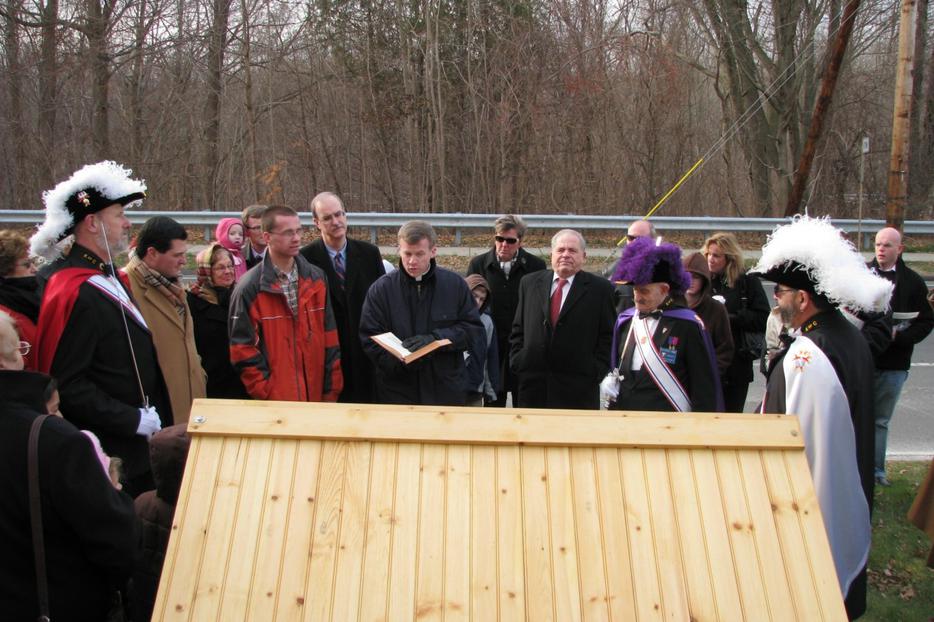 Donald Creatore in red tie stands to the right side as his pastor blesses the creche on town hall green.