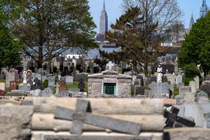 The Empire State Building is seen in the distance behind the tombstones at Calvary Cemetery on May 10, 2020, in the Queens borough of New York City, after the Archdiocese of New York lifted COVID-related cemetery-visitation restrictions for Mothers Day.