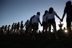 Students and family members holds hands Feb. 18 around a makeshift memorial in front of Marjory Stoneman Douglas High School, where 17 people were killed Feb. 14 in Parkland, Florida. 