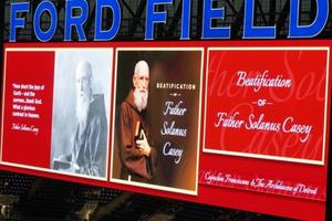 Above, the JumboTron announces the holy event at Ford Field Nov. 18; below,  the thousands in attendance, Cardinal Angelo Amato celebrating the Mass, and the official portrait of Blessed Solanus Casey seen center stage.