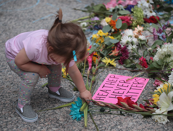 A young girl puts flowers on a memorial to Heather Heyer that was chalked on the pavement during a demonstration on August 13, 2017 in Chicago, Illinois. Heyer was killed and 19 others were injured in Charlottesville, Virginia when a car plowed into a group of activists who were preparing to march in opposition to a nearby white nationalist rally.