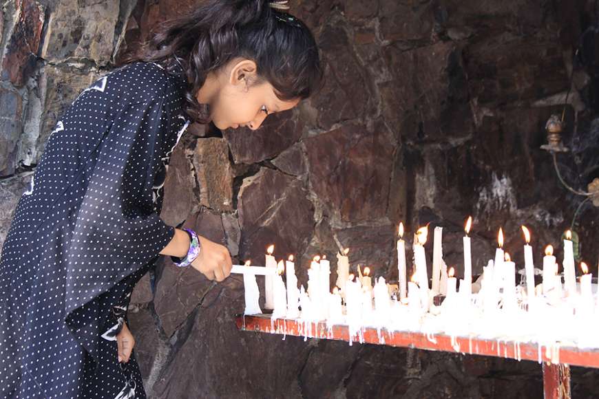 A young girl lights a candle at a Marian grotto in Pakistan. 