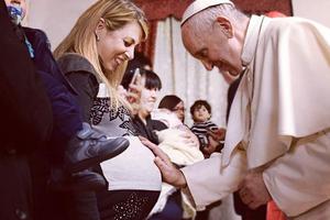 Pope Francis blesses an expectant mother.