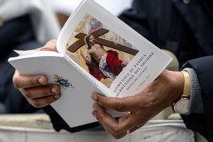 A pilgrim follows along with a booklet as Pope Francis celebrates Easter Mass and the Urbi et Orbi Blessing in St. Peter's Square, April 22, 2019.