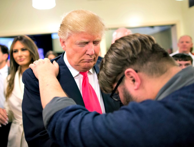 Pastor Joshua Nink prays with Republican presidential candidate Donald Trump, who was raised Presbyterian, after a service at First Christian Church on Jan. 31 in Council Bluffs, Iowa. Below, Hillary Clinton attend a service at the First United Methodist Church in Huntington, W. Va.